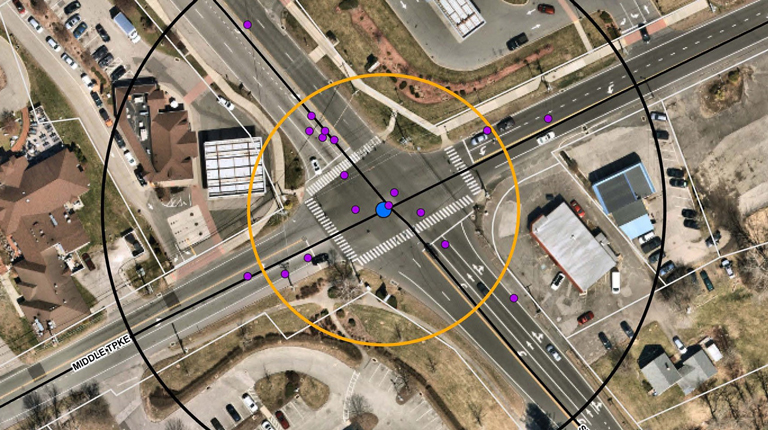 Aerial view of a pink three-way roundabout, showing the rooftops and rooftop parking lots of nearby buildings.