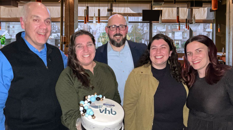 VHB employees holding a cake. 