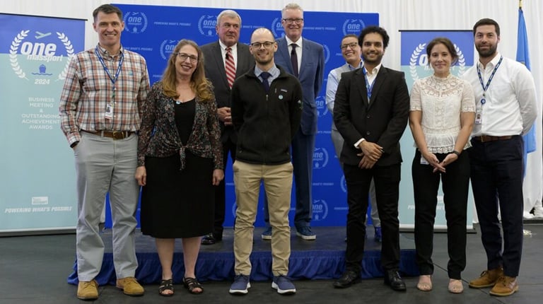 Nine VHB and Massport team members stand together on stage at the One Massport Business Meeting to accept the Outstanding Achievement Award.  