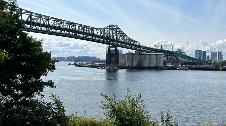 A bridge over water with an industrial plant below it.