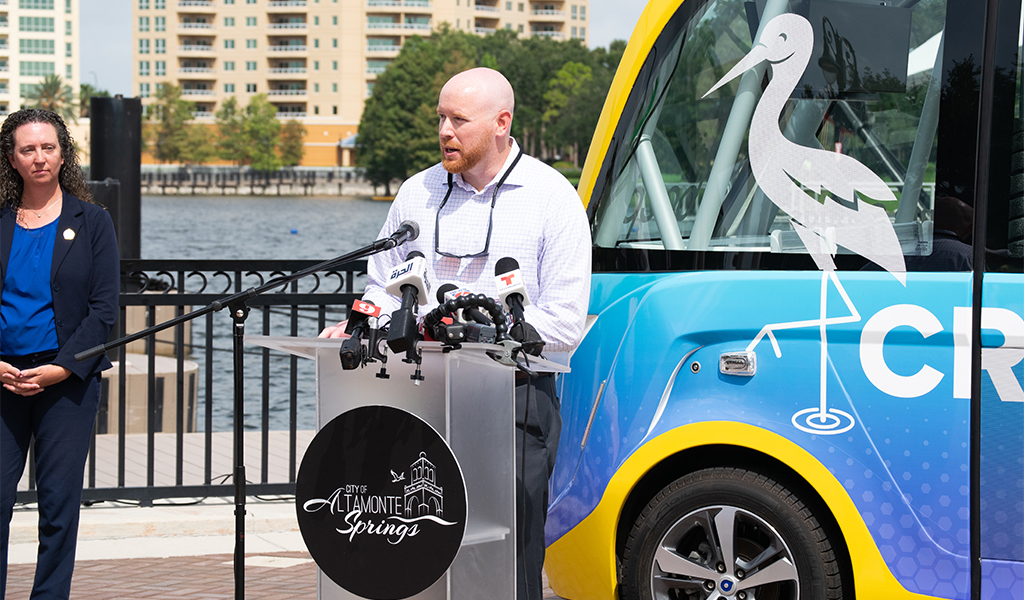 Ryan Fetchko stands in front of an autonomous vehicle at a speakers podium