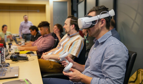 VHB employee uses virtual reality headset while sitting at a conference table with five other people.