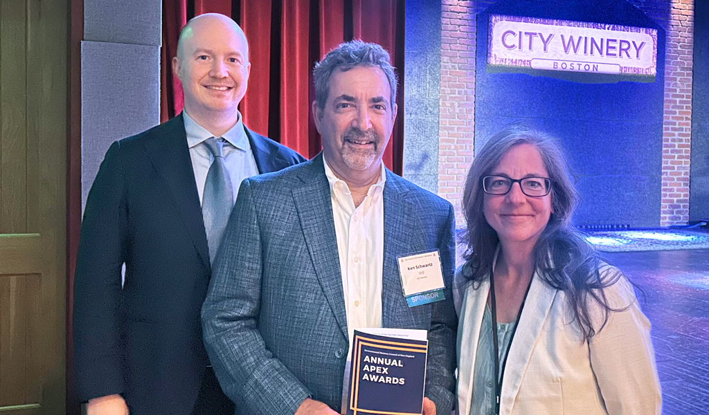 Three individuals stand on stage at City Winery, smiling with one person holding an 'EBC Annual Awards' program.
