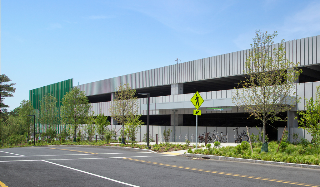 A three-story parking garage with newly planted landscaping. 