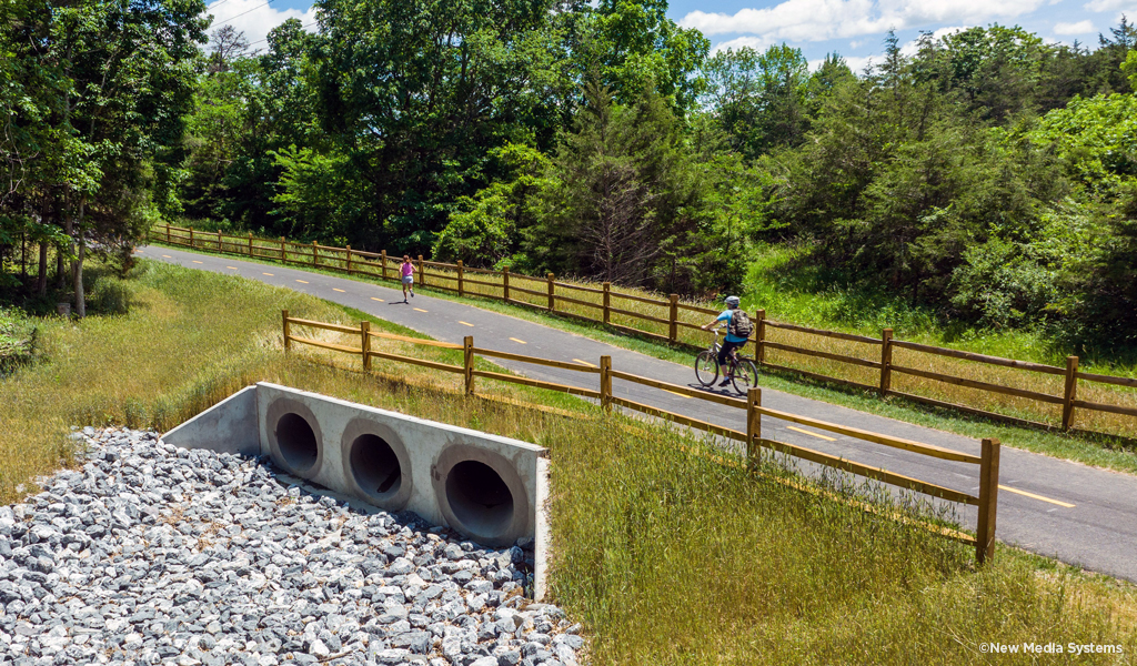 One bike rider and one runner use a section of the trail built across a culvert.