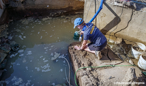 An archaeologist pumps river water out of a current excavation area. 