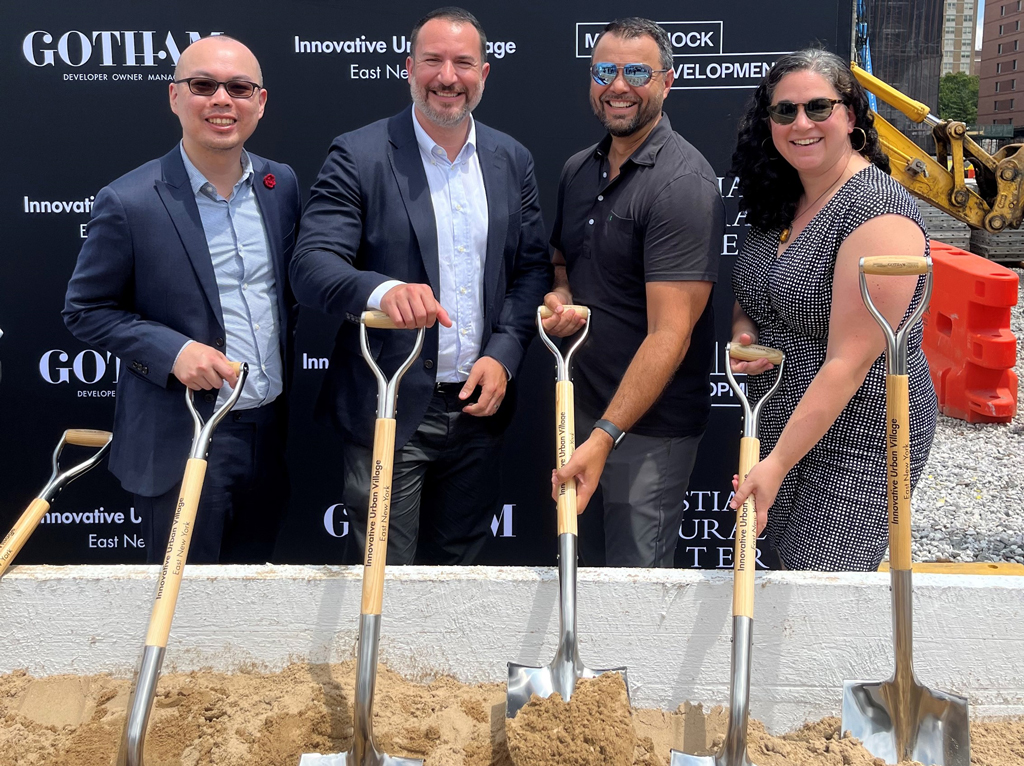 Men and women standing with shovels in dirt.
