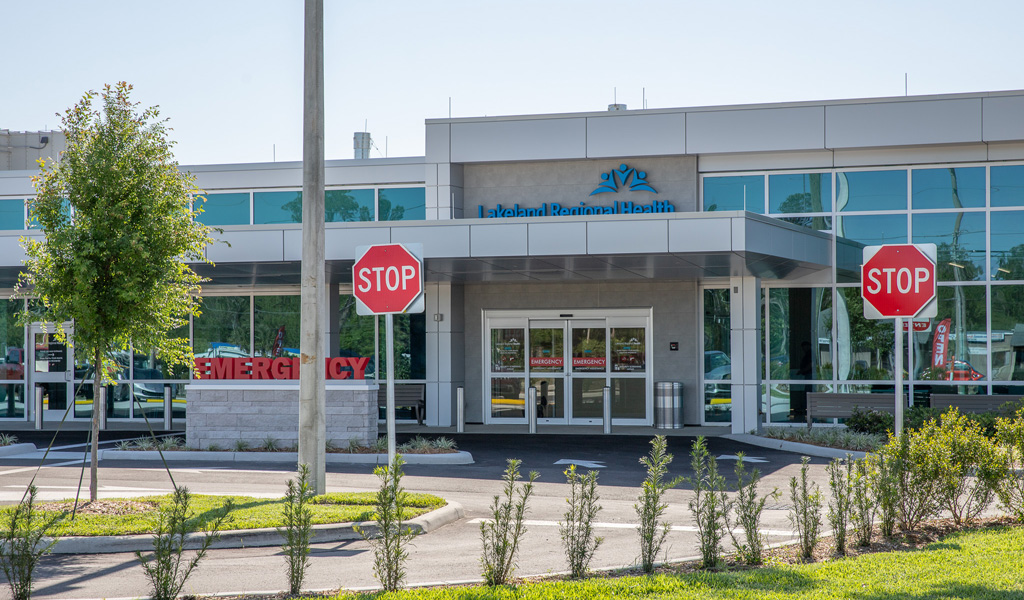 Two stop signs in front of an emergency department.