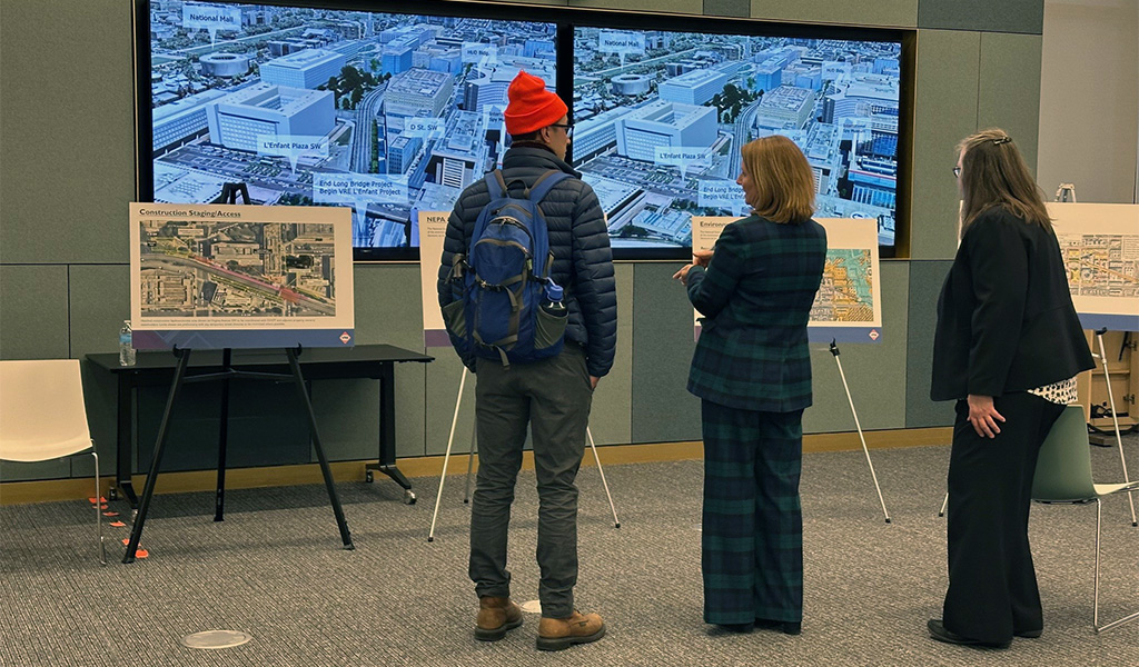 Three people review the project maps on display at the open house.