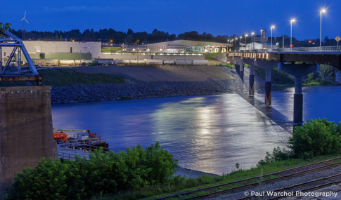 Nighttime view of a bridge over river, with a border crossing facility in the background.