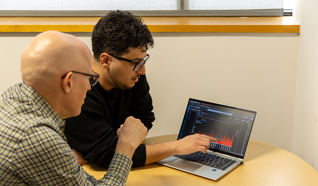 Nader Lobandi and Greg Bosworth discuss a project while looking at a laptop