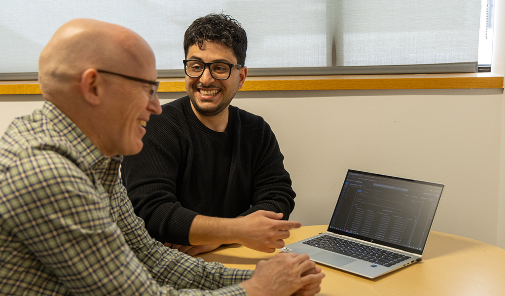 Nader and Greg share a laugh while sitting next to the laptop