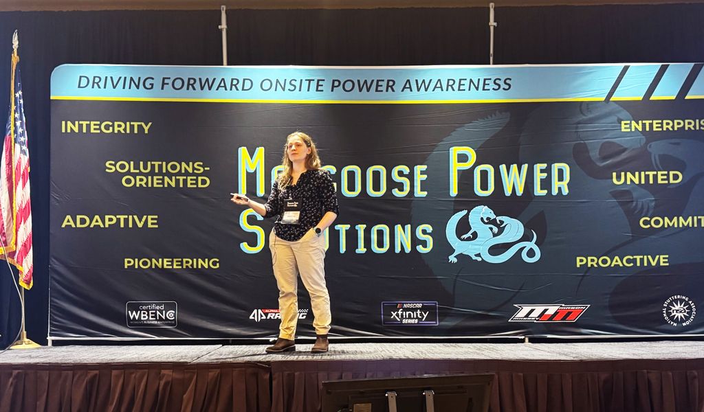 Person presenting on a podium with a banner reading "Mongoose Power Solutions" visible in background.