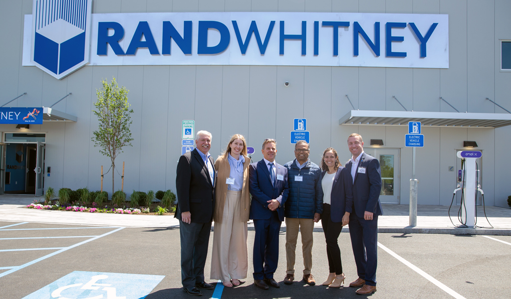 Ted Fire, Annie Gorman, Nick Smith, Vinod Kalikiri, Brittany Gesner, and Kyle Merkosky stand in front of an industrial facility.