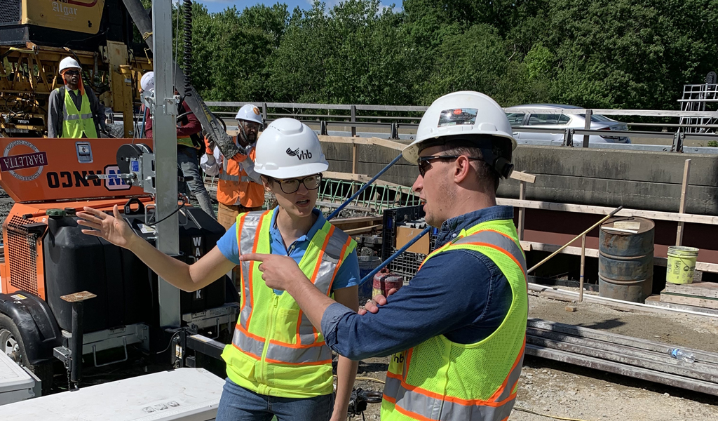 Olivia Richards in safety gear standing on a construction site talking with a man in safety gear