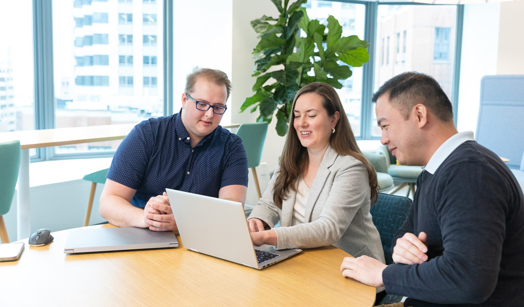 Gavin Graham and colleagues brainstorming in the office casual space near the shuffleboard table.