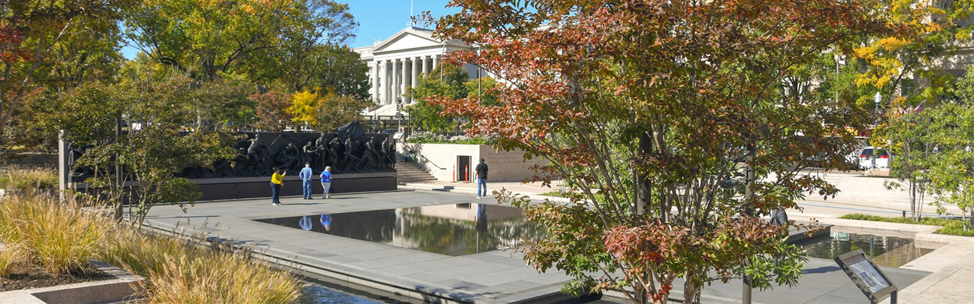 A sculpture of soldiers in an outdoor setting with water and vegetation.