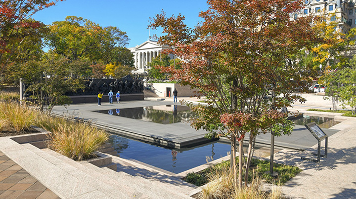 A sculpture of soldiers in an outdoor setting with water and vegetation.