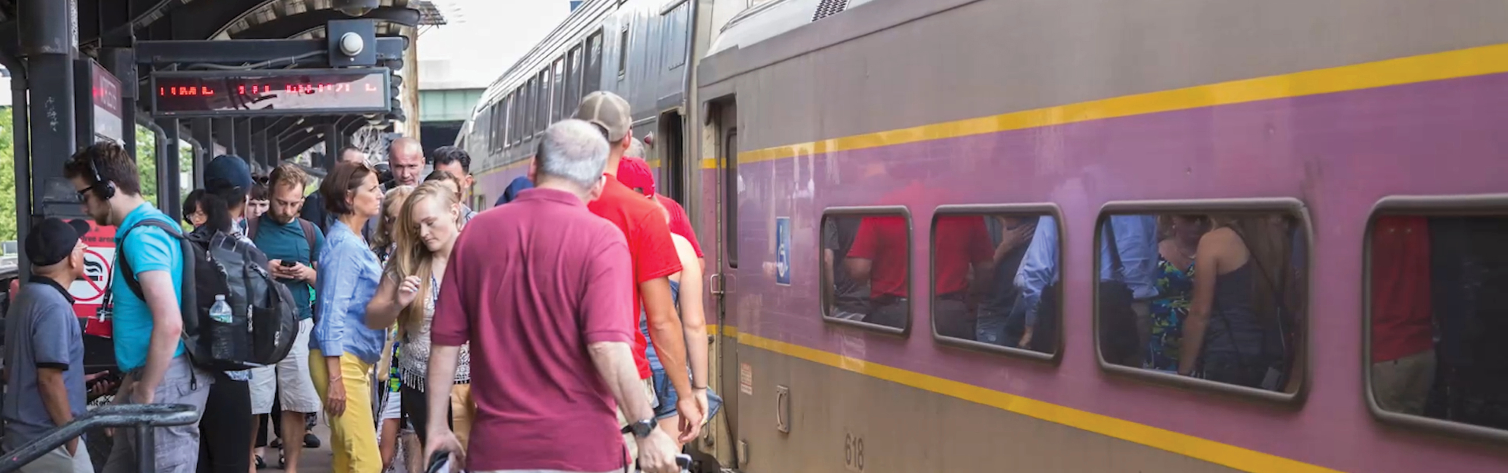 People board and deboard a train at a crowded station